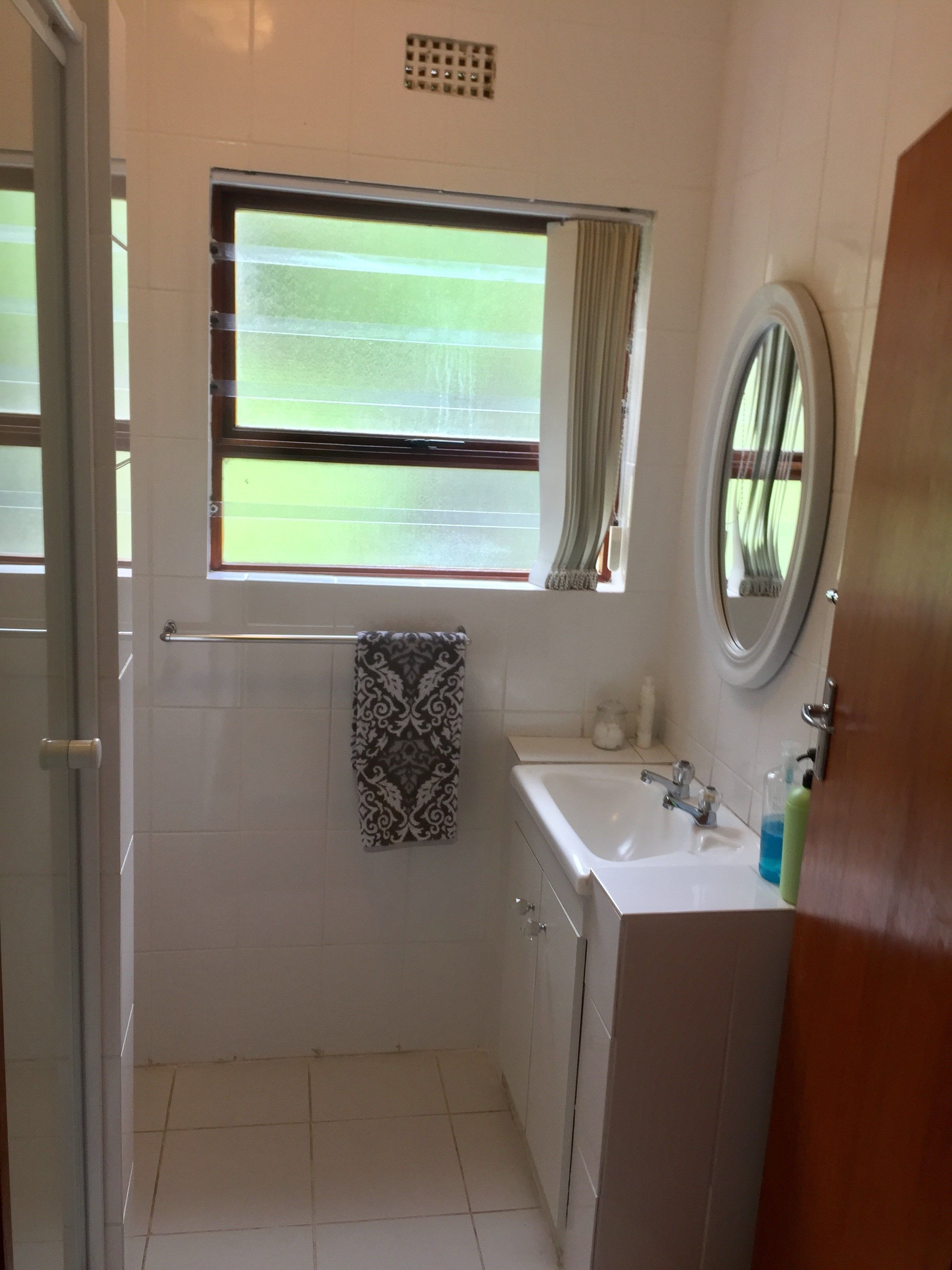 Un baño con ventana, una toalla, un lavabo y un espejo.