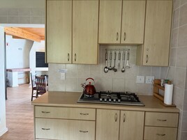 Una cocina con armarios de madera, estufa a gas y tetera.