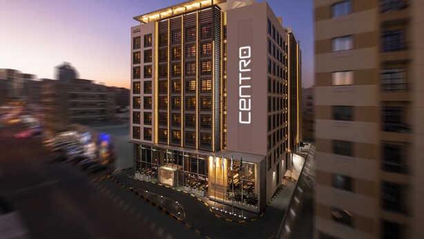 Um hotel moderno com um destaque para a placa 'CENTRO', com uma grade de janelas e design de telhado plano.