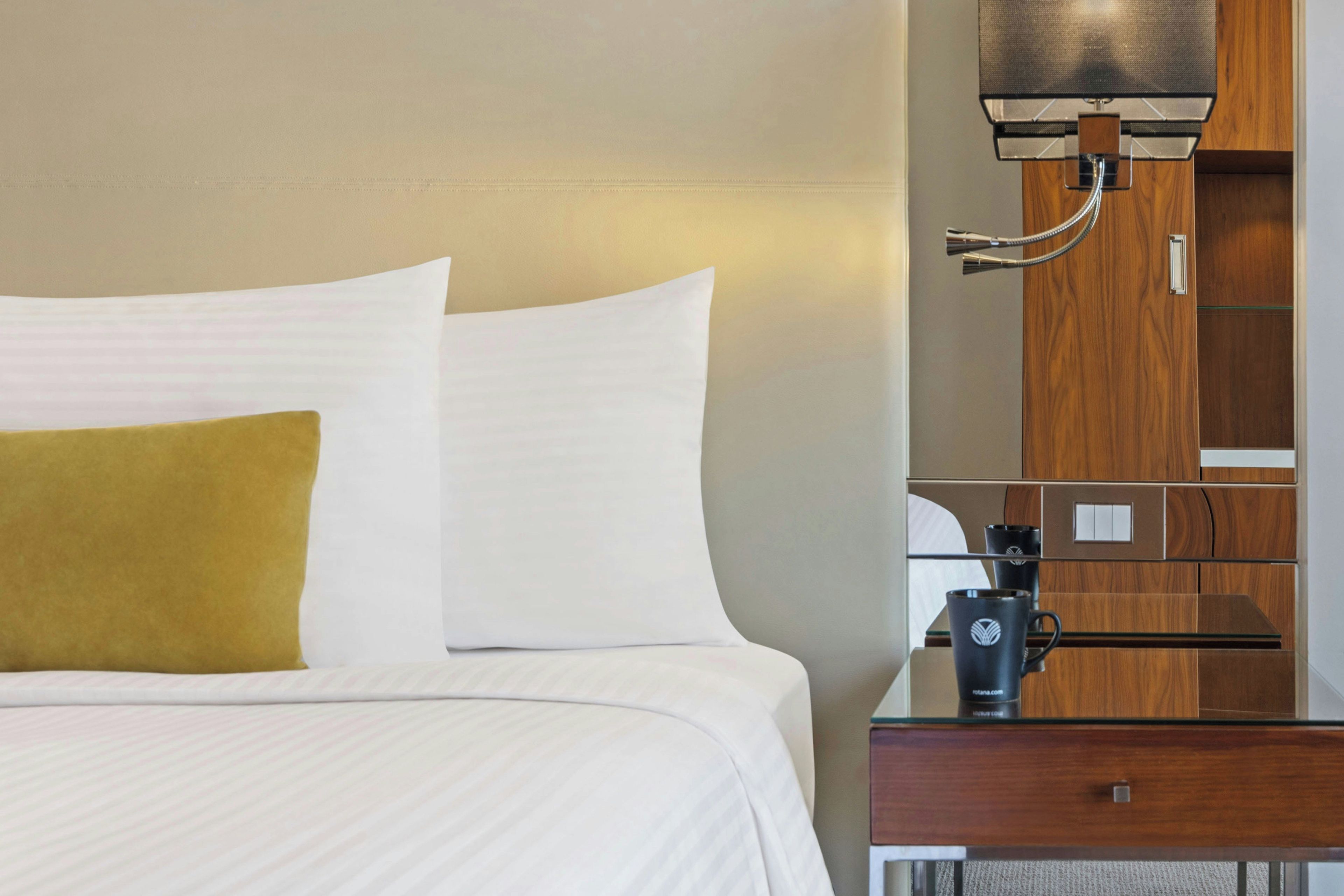 Une chambre d’hôtel comprenant un lit, une table de chevet, une machine à café et une armoire en bois.