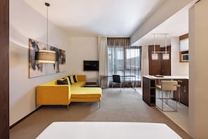 A modern hotel room with a yellow sofa, a dining area with a bar, and a large window with curtains. - Centro Capital Doha By Rotana (Doha)