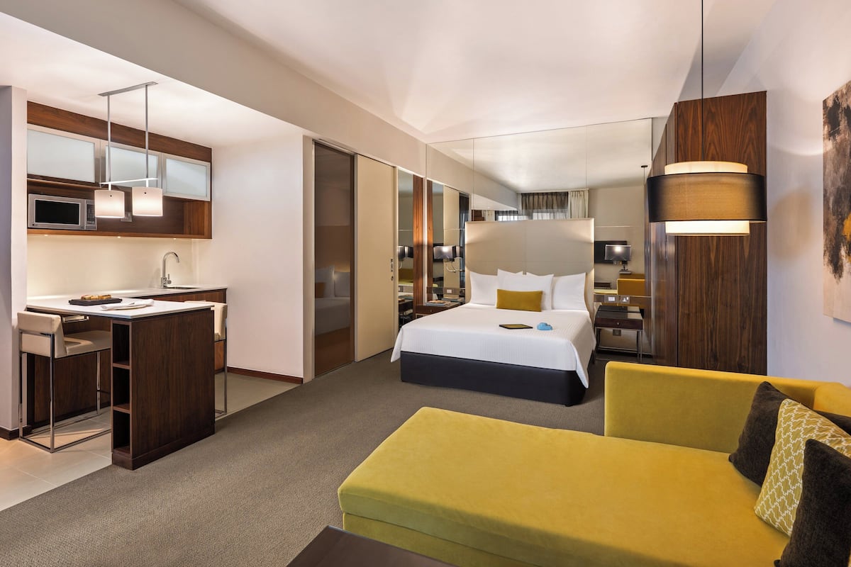 A modern hotel room with a bed, a desk, a sofa, and a large mirror.