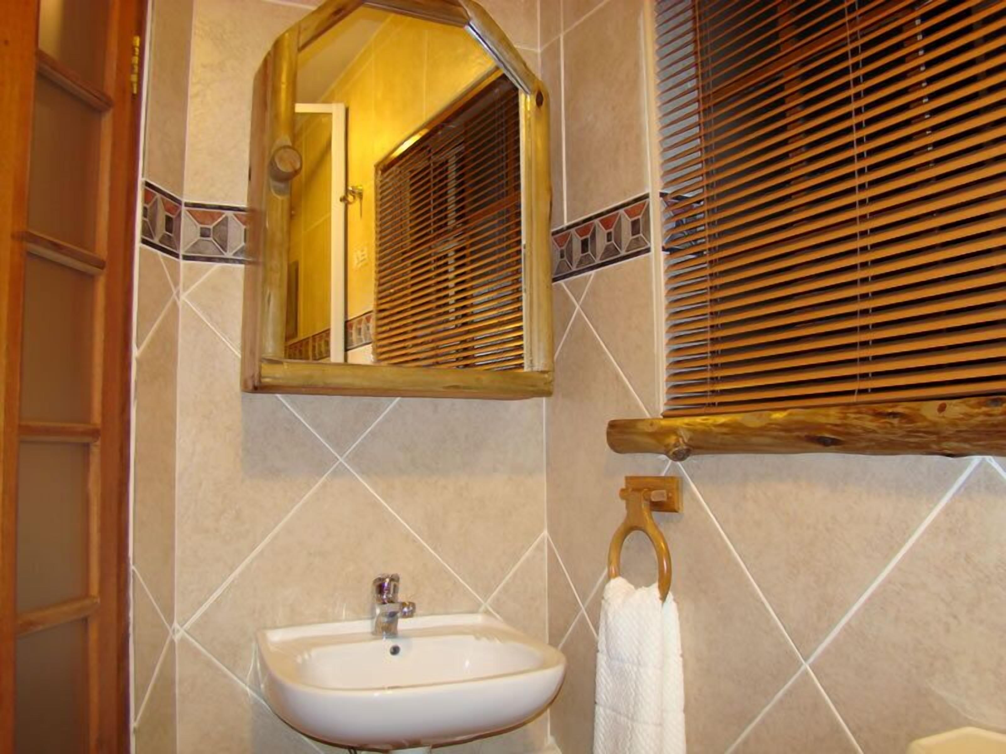 A bathroom with a white sink, a mirror, and wooden blinds.