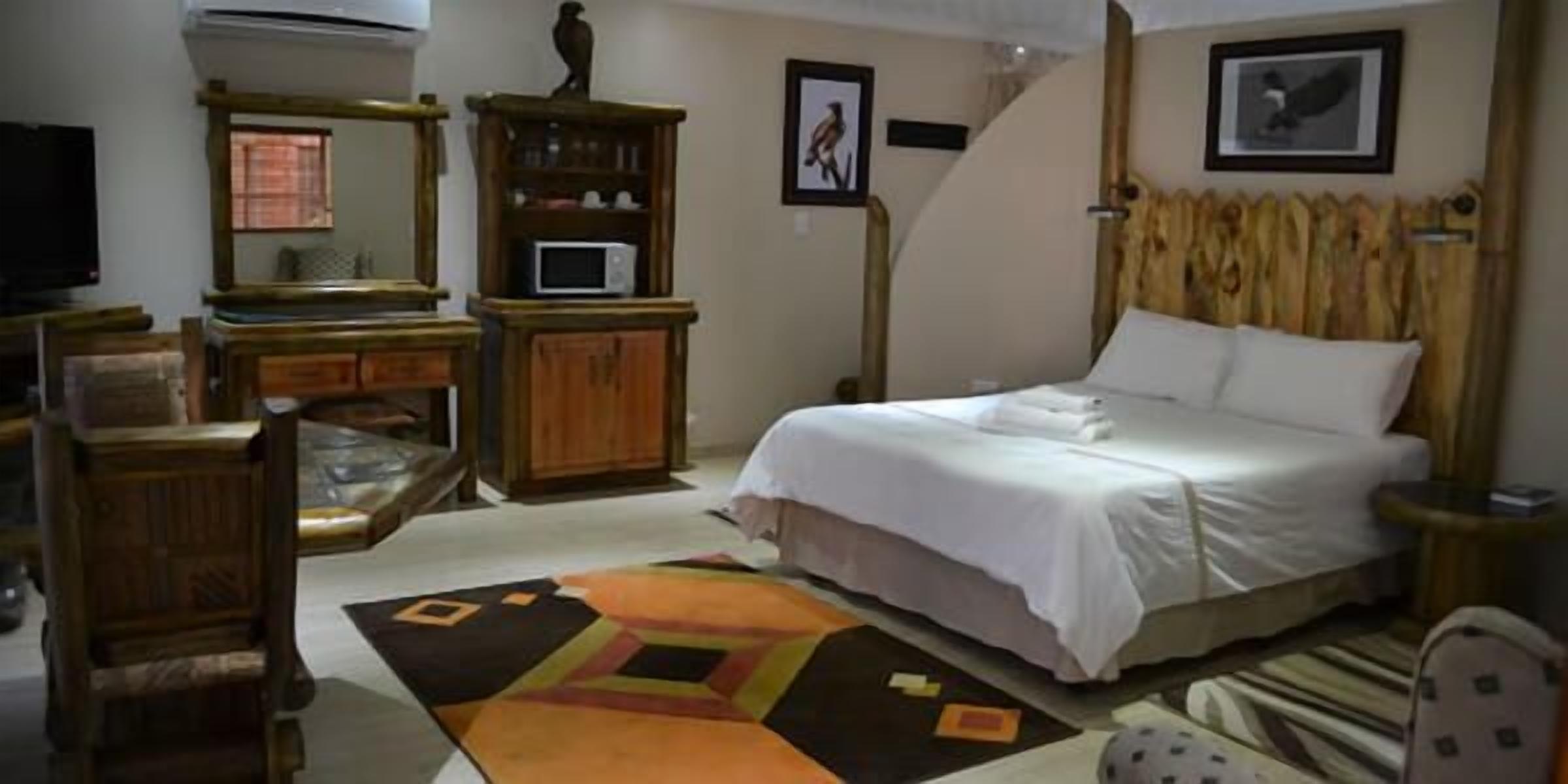 Un dormitorio con cama, escritorio, silla, televisor y microondas.