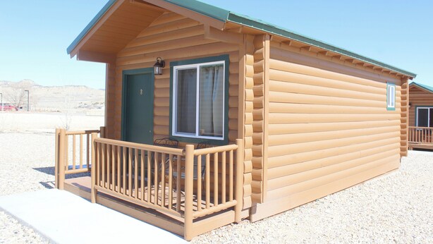 A log cabin with a porch, a window, and a door. - Bryce Valley Lodging (Tropic)