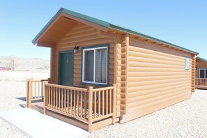 A log cabin with a porch, a window, and a door.