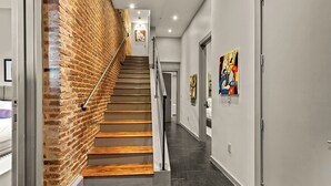 Een modern interieur met een bakstenen muur, een houten trap en kunstwerken aan de muren.