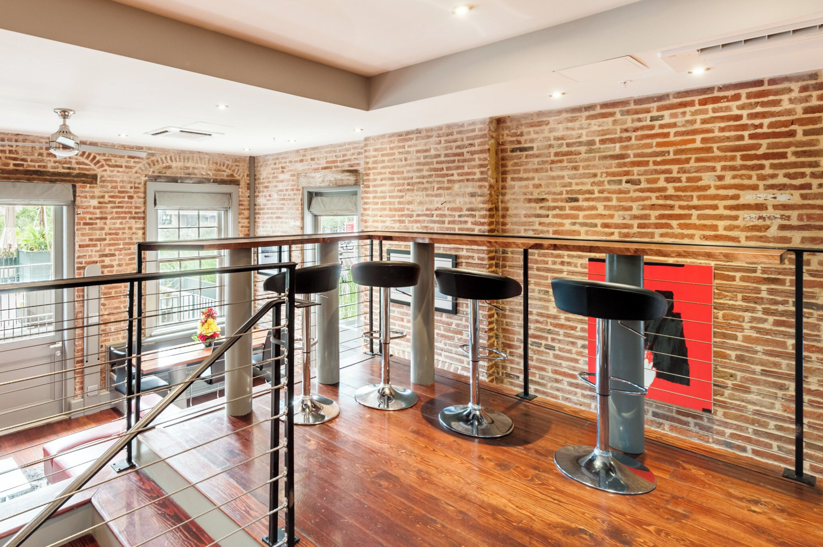 A modern interior with a brick wall, wooden flooring, and metal railings.