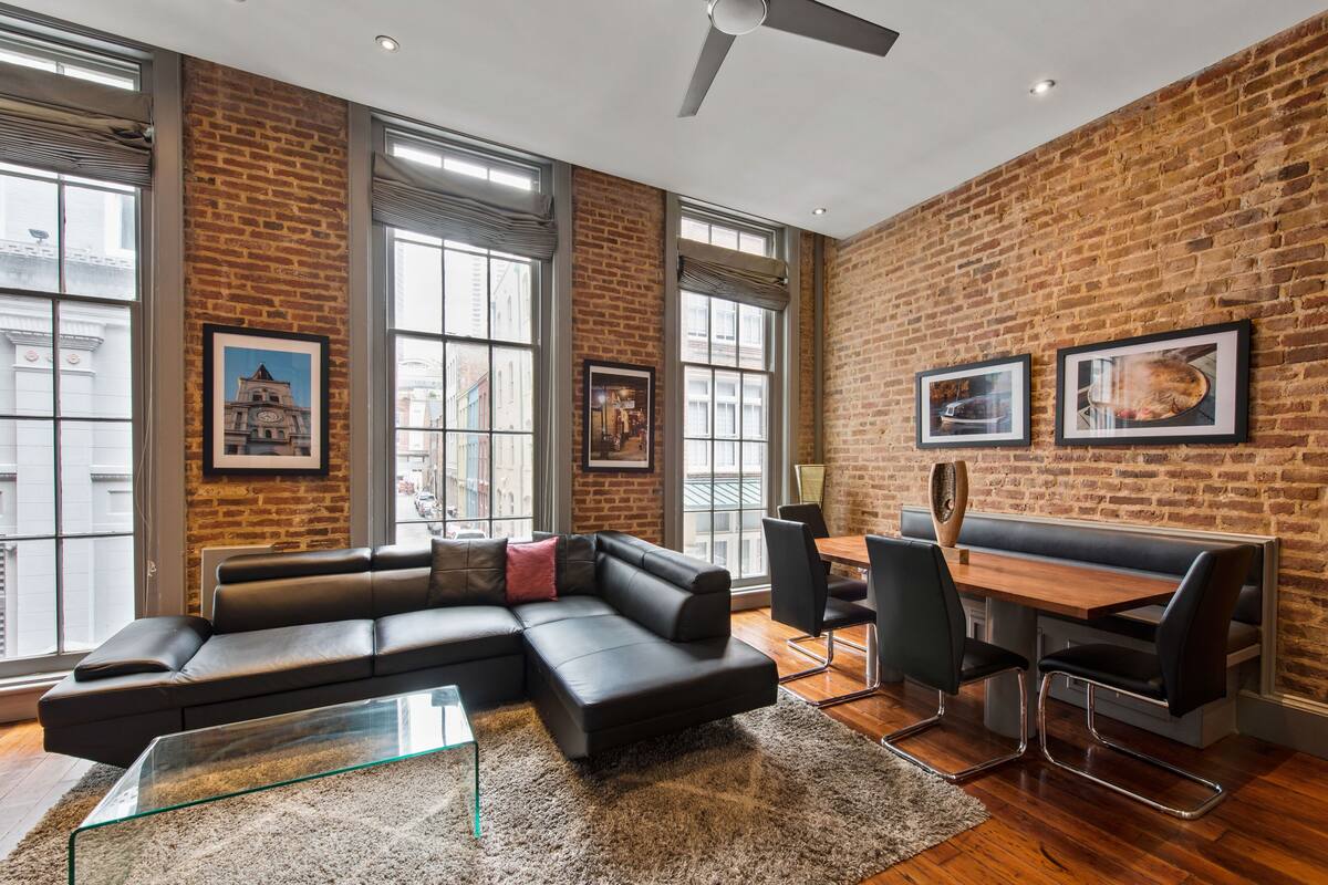A modern living room with a sectional sofa, a glass coffee table, and a dining area with a wooden table and chairs.