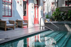 Un espace piscine avec une porte rouge, des chaises en bois et un mur en pierre.