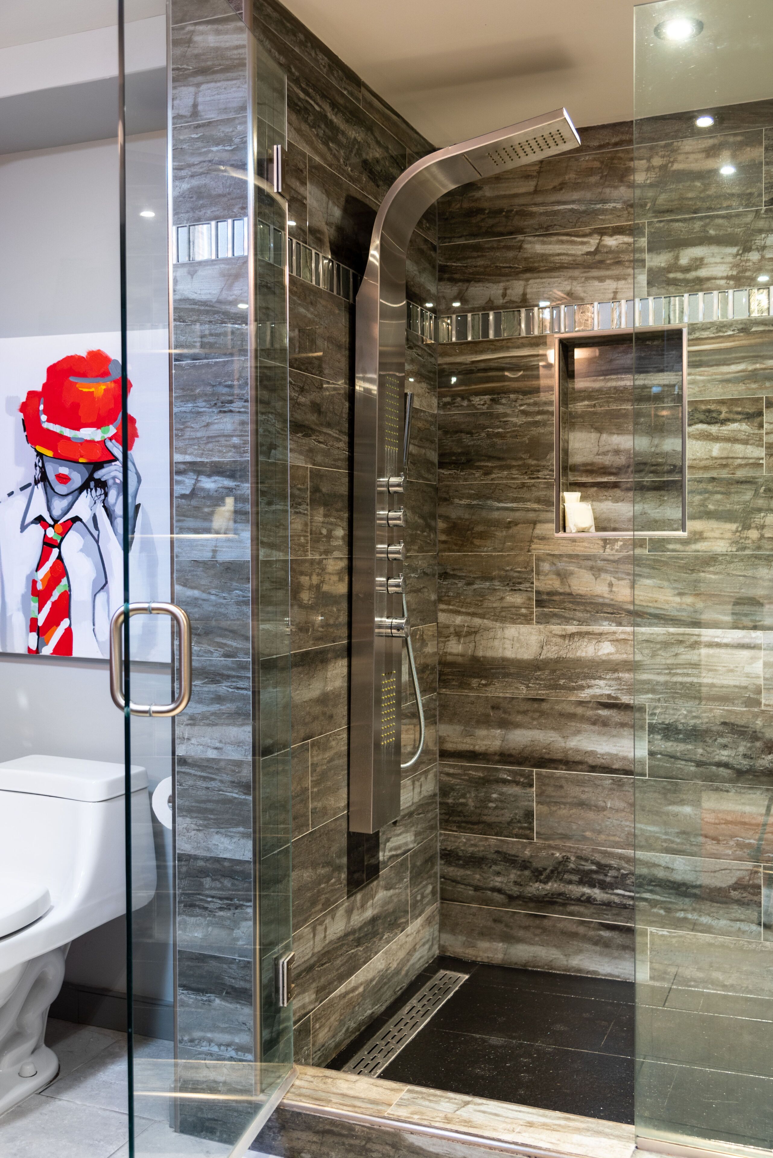 Une salle de bain moderne avec une douche à parois de verre, des murs en marbre et des toilettes blanches.