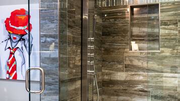 Une salle de bain moderne avec une douche à parois de verre, des murs en marbre et des toilettes blanches.