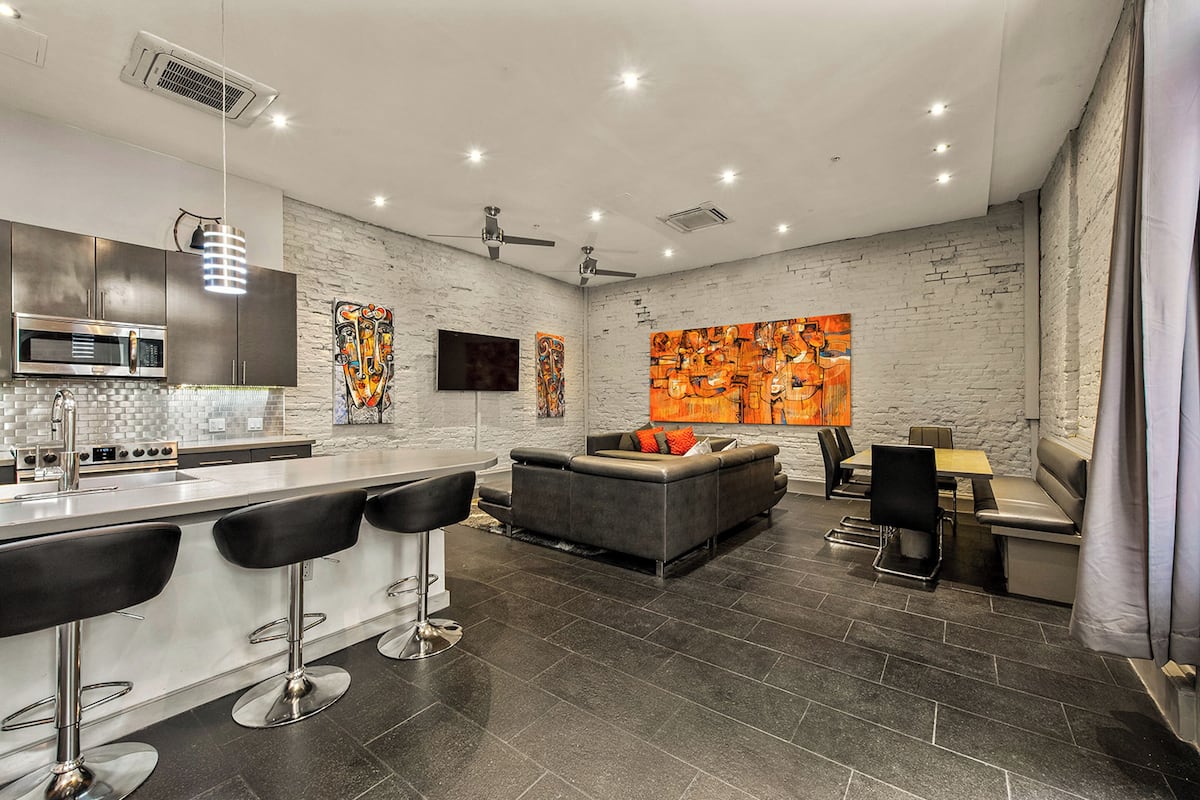 A modern kitchen with a bar area, a seating area with a sofa and chairs, and a dining table.