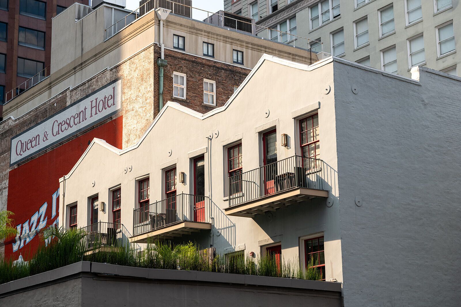 The exterior of the Queen & Crescent Hotel, featuring a modern facade with balconies and a large mural of a jazz band.