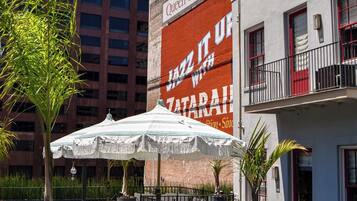 A hotel with outdoor seating, a large mural, and a view of a tall building.