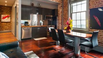 A modern kitchen with dark cabinets, stainless steel appliances, and a brick wall.