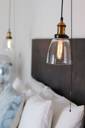 Un dormitorio con una cama, cabecera y lámpara colgante.