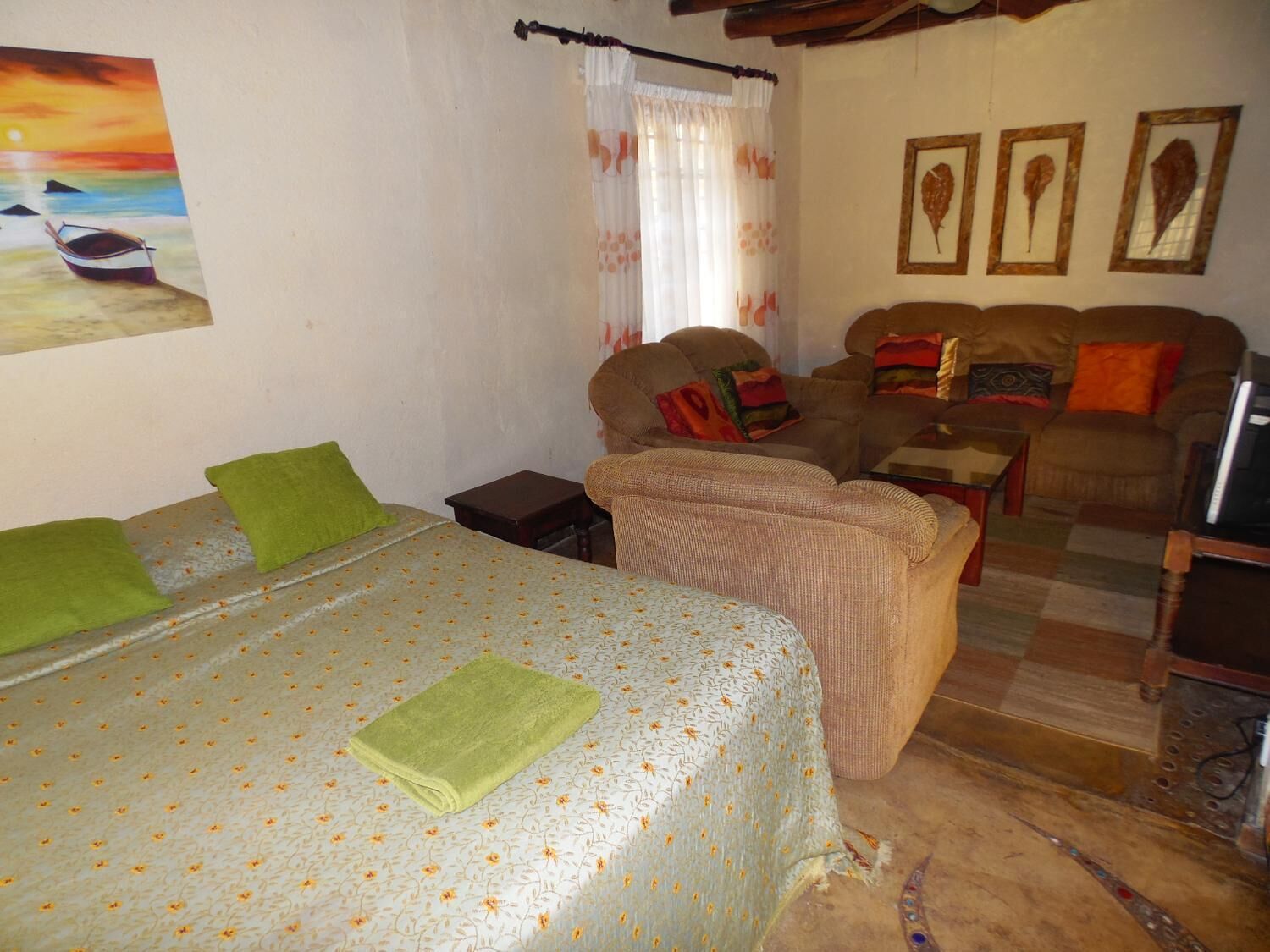 A cozy room with a bed, a sofa, a small table, and a television.