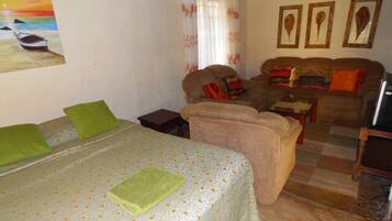 A cozy room with a bed, a sofa, a small table, and a television.