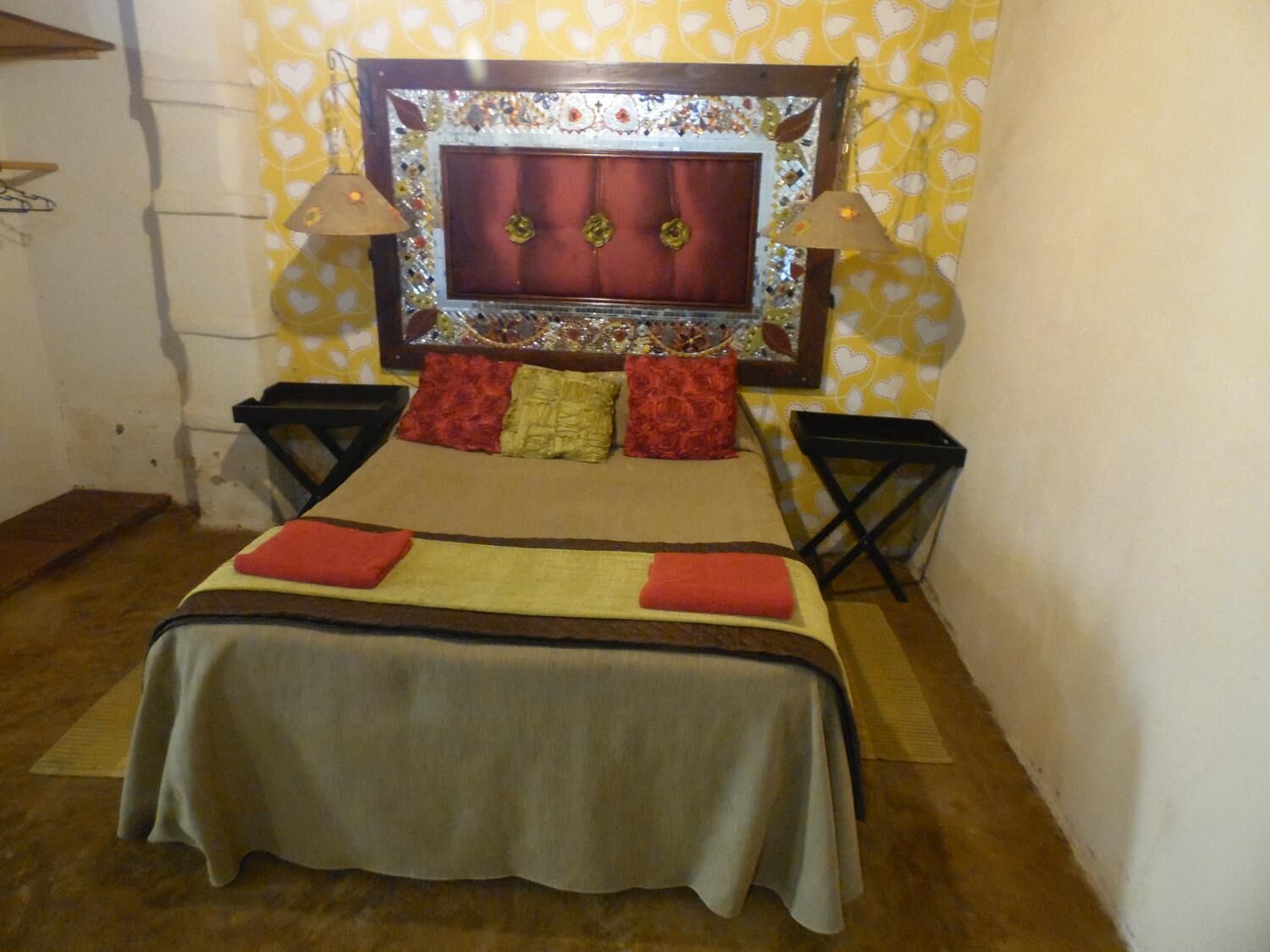 Una cama con cabecera, dos mesitas de noche y un papel tapiz estampado.