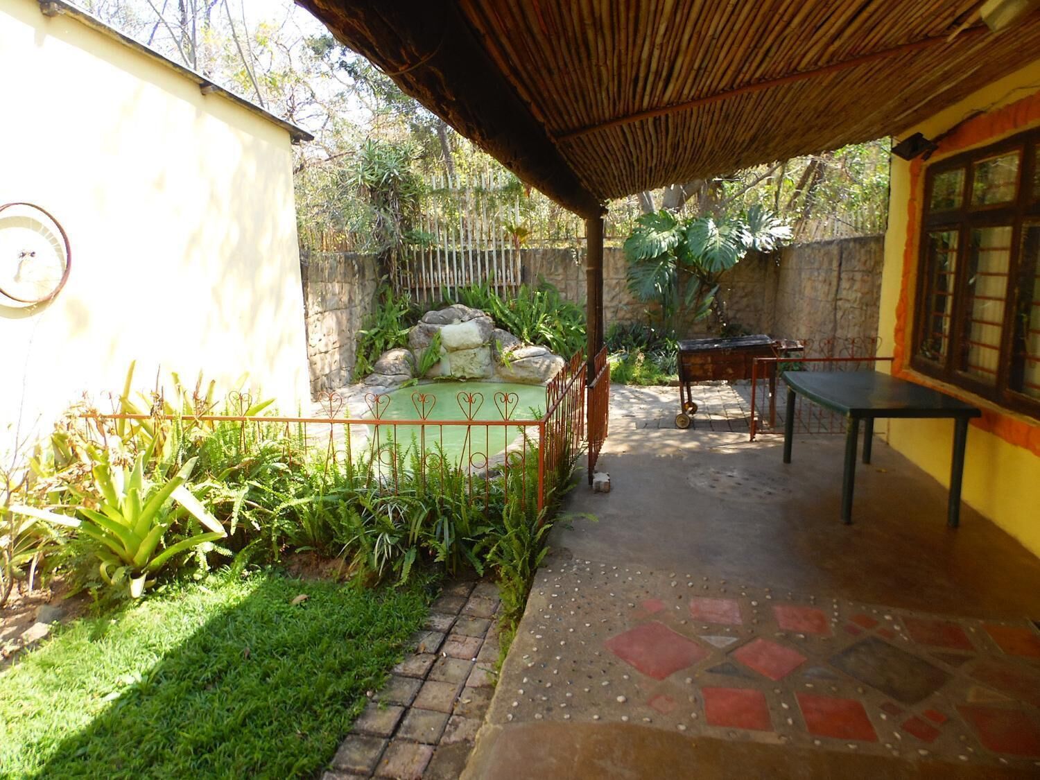 A covered outdoor area with a stone floor, a small pond, and a table.