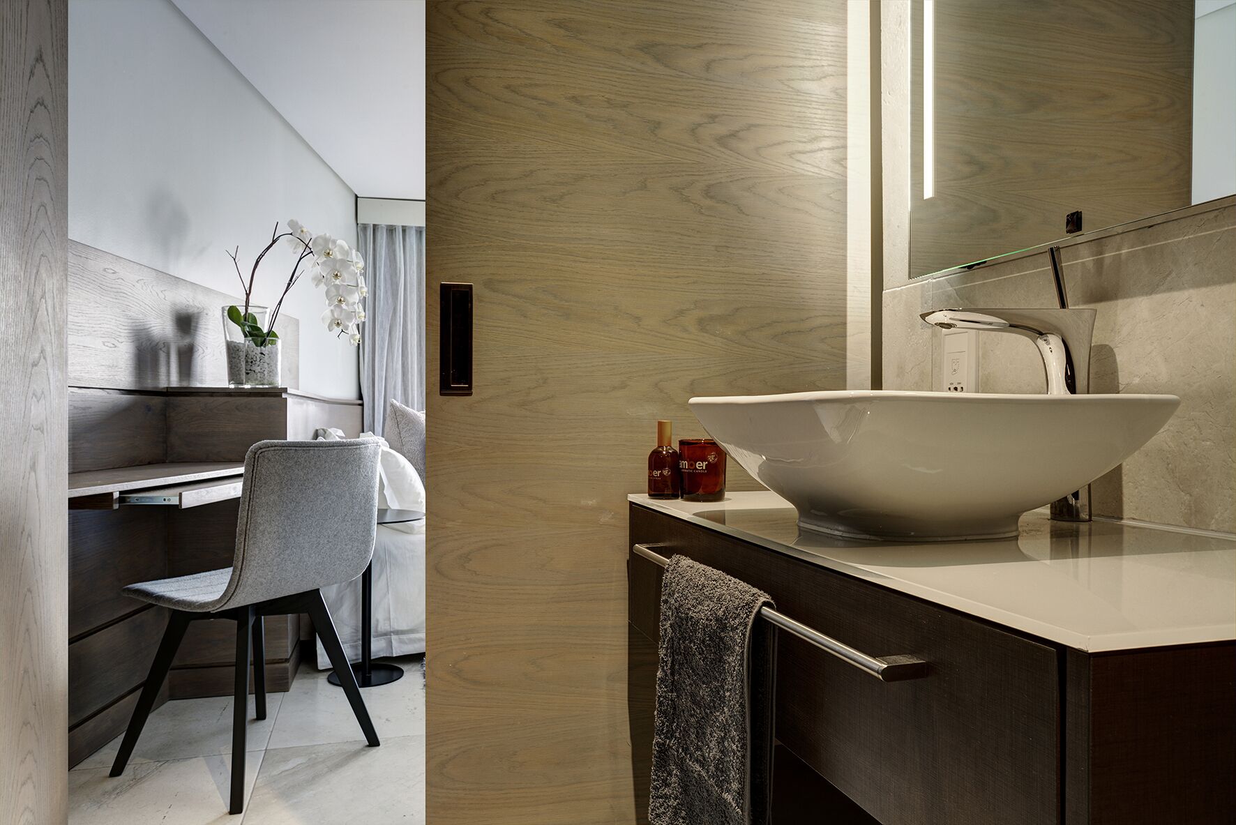 A modern bathroom with a large vessel sink, a wooden vanity, and a chair.