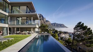 Et moderne hotel med en roolftop-infinity-pool med udsigt over et bjergrigt landskab.