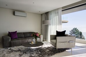 A modern living room with a grey sofa, a round coffee table, and a grey armchair.