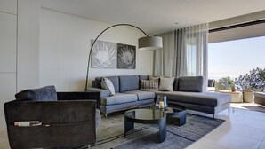 En moderne stue med en grå sofa, en sort lænestol og et sofabord. To abstrakte kunstværker hænger over sofaen.