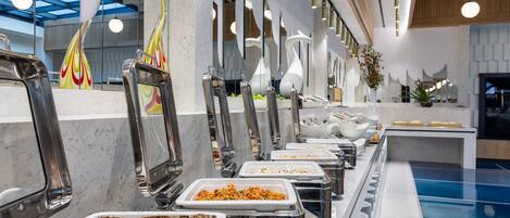 A buffet area with multiple serving stations, a marble countertop, and a pool in the background.