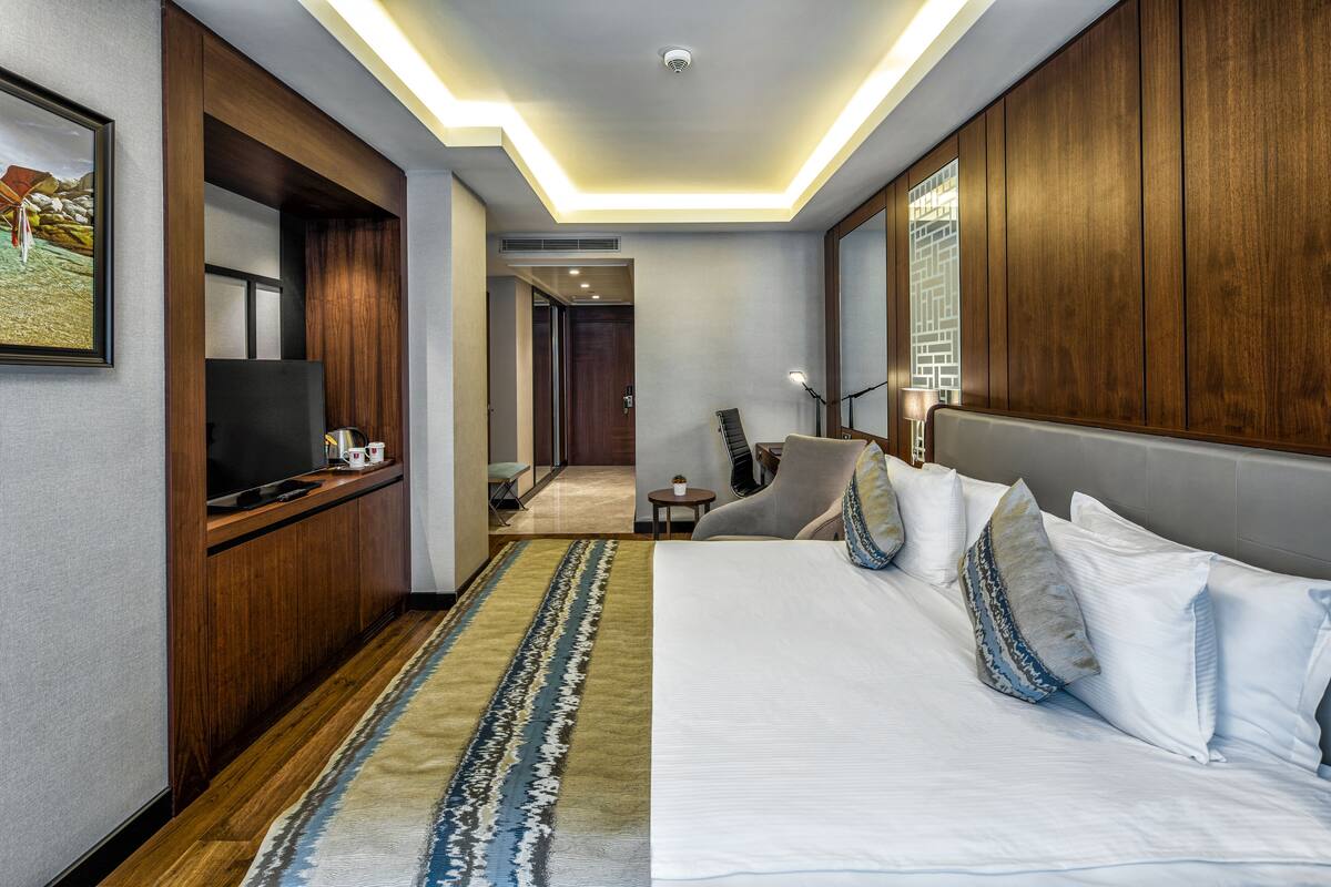 A hotel room with a large bed, a TV, a desk, and a chair.
