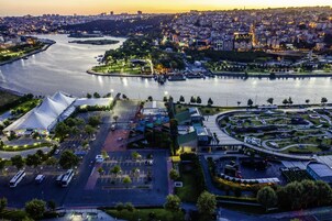 An aerial view of a cityscape with a river, a stadium, and a park.