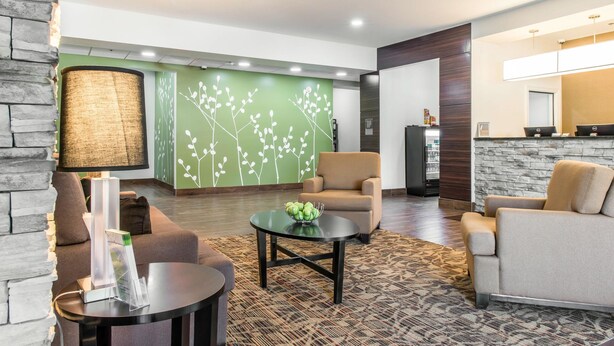 Un vestíbulo moderno con una pared verde, una recepción y zonas de estar cómodas.