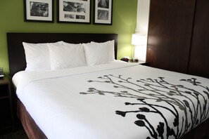 A neatly made bed with white linens and a floral-patterned bedspread. There are three framed pictures on the wall above the bed.