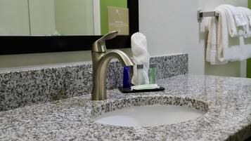 A bathroom sink with a modern faucet, a towel rack with folded towels, and toiletries on the countertop.