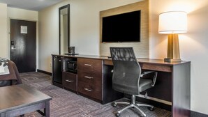Habitación de hotel con escritorio, silla, televisor y lámpara.