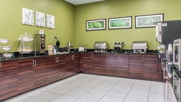 A modern kitchen with a green wall, framed artwork, and various appliances.