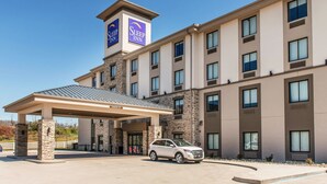 Un hotel Sleep Inn con entrada techada, varios pisos y una zona de estacionamiento.