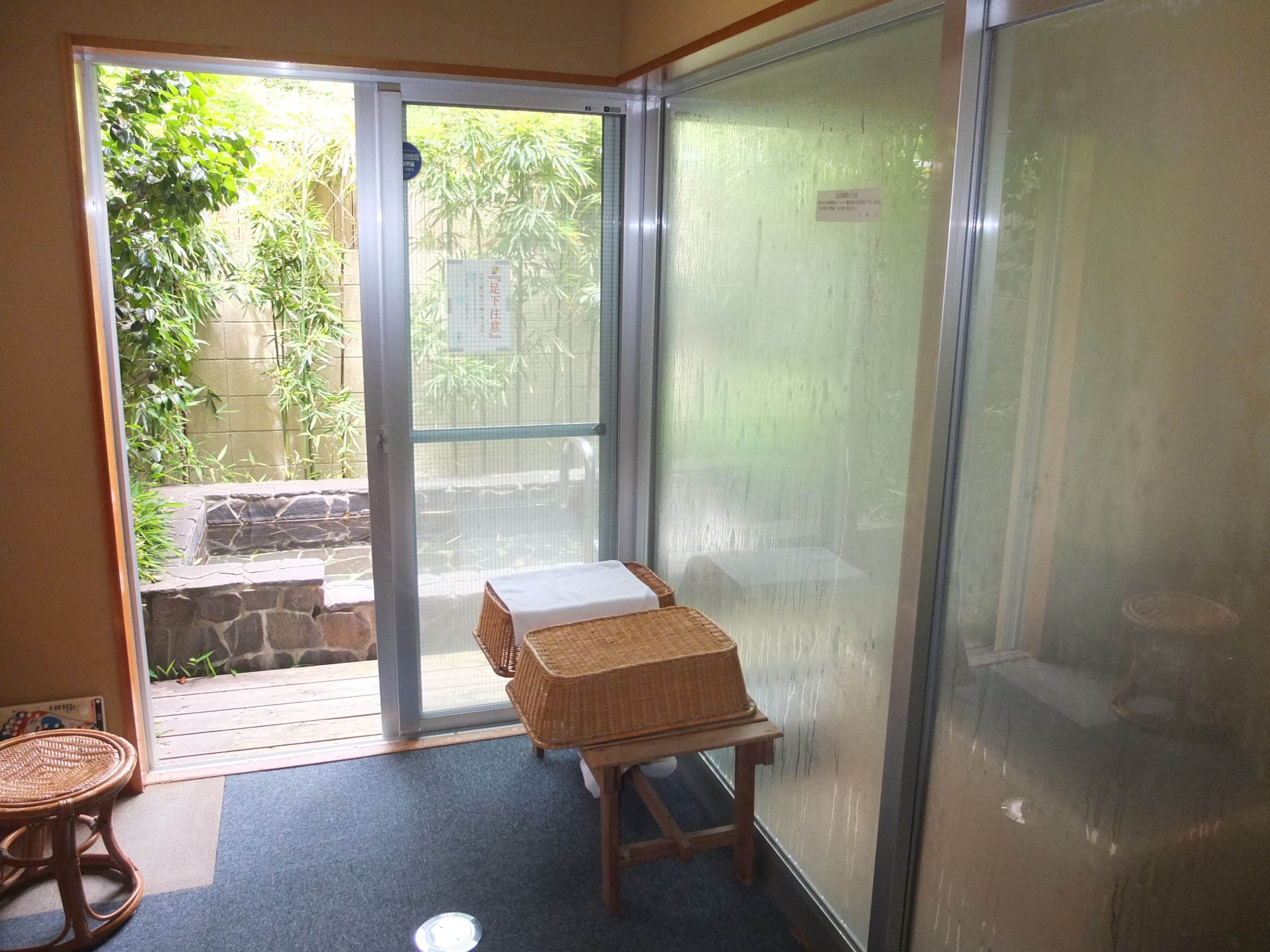 A room with a sliding glass door leading to a patio area with a wicker table and a wicker chair.