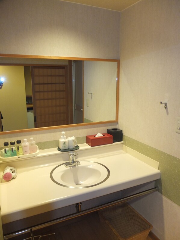 A hotel bathroom with a sink, mirror, and toiletries.