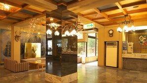 A lobby with a reception desk, seating area, and a large vase with flowers. - Nikko Green Hotel Natsukashiya Fuwari (Nikko)