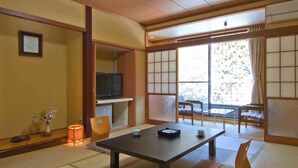 A traditional Japanese room with tatami flooring, a low table, chairs, a television, and a view of the outdoors. - Nikko Green Hotel Natsukashiya Fuwari (Nikko)