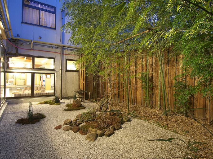 Ein traditioneller japanischer Garten mit Kieswegen, Steinen und Bambuspflanzen.