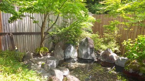 A garden with a pond, rocks, and various plants. - Nikko Green Hotel Natsukashiya Fuwari (Nikko)