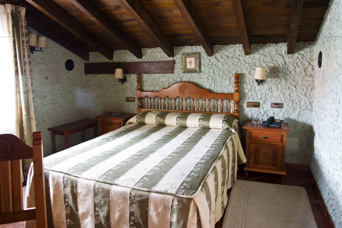 Un dormitorio con una cama de madera, una mesita de noche y una pared de piedra.