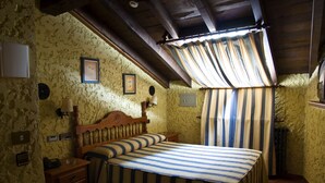 A bedroom with a wooden bed, a nightstand, a lamp, and a radiator. - La Casona de Luis (Santillana del Mar)