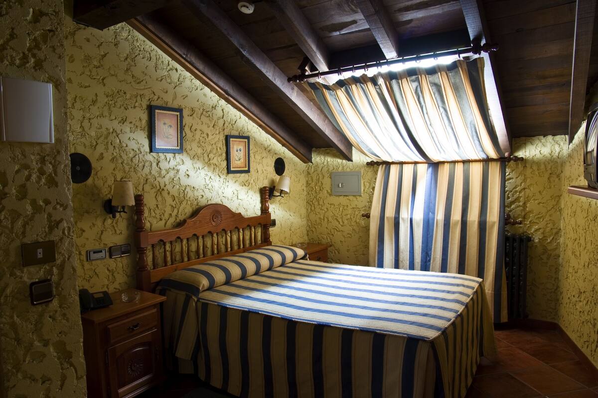 Un dormitorio con cama de madera, mesita de noche, lámpara y radiador.