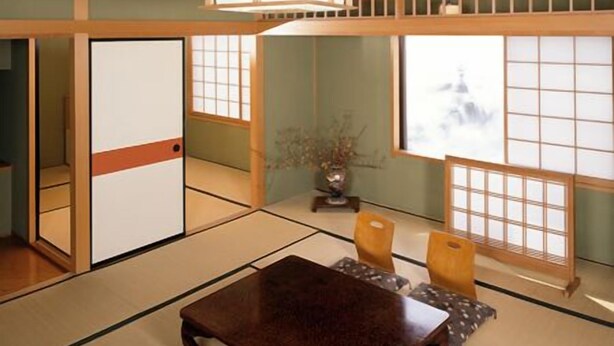 Una habitación japonesa tradicional con suelo de tatami, una mesa baja y puertas correderas.