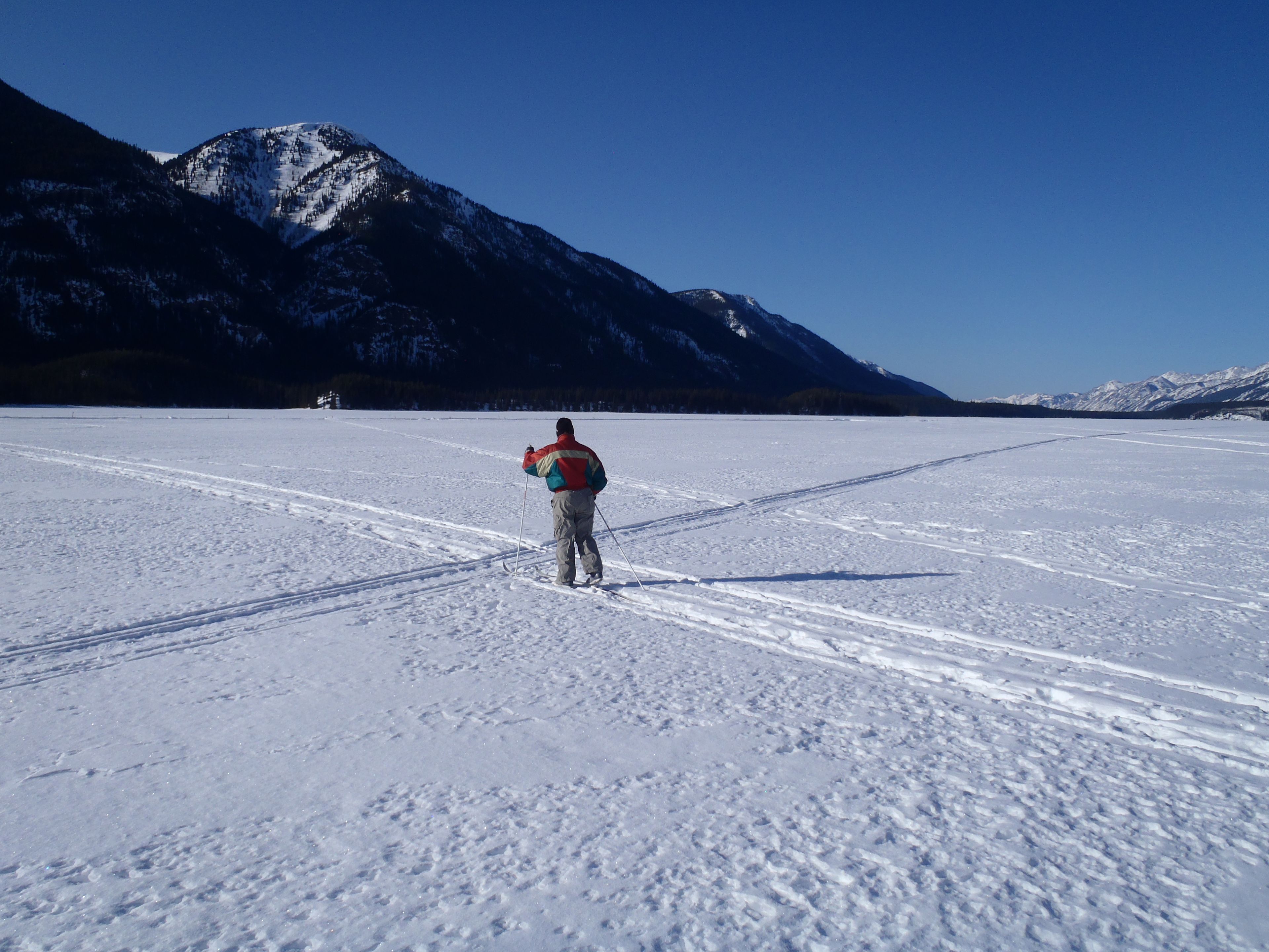 A person skiing on a flat, snowy surface with mountains in the background.