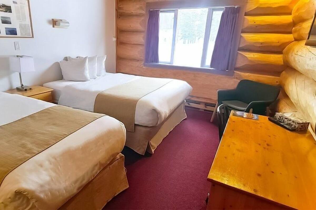 Habitació d'una cabana de fusta amb dos llits, una taula i una cadira.